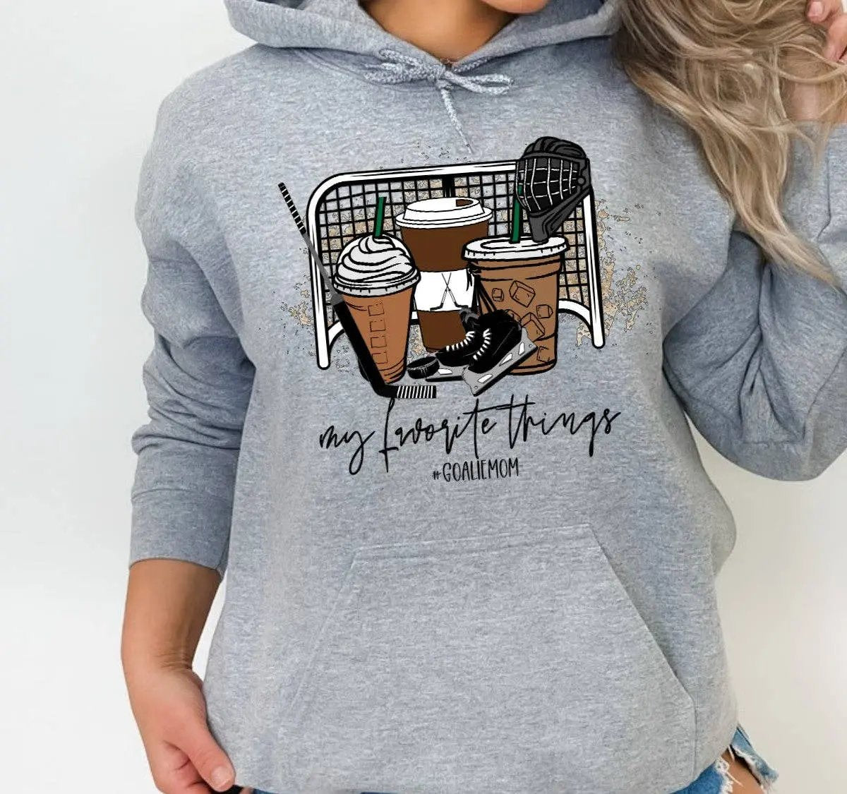 Woman wearing grey 'Goalie Mom' hoodie with 'My favourite things' graphic including coffee cups, skates and hockey gear – Maple Stick Hockey product.