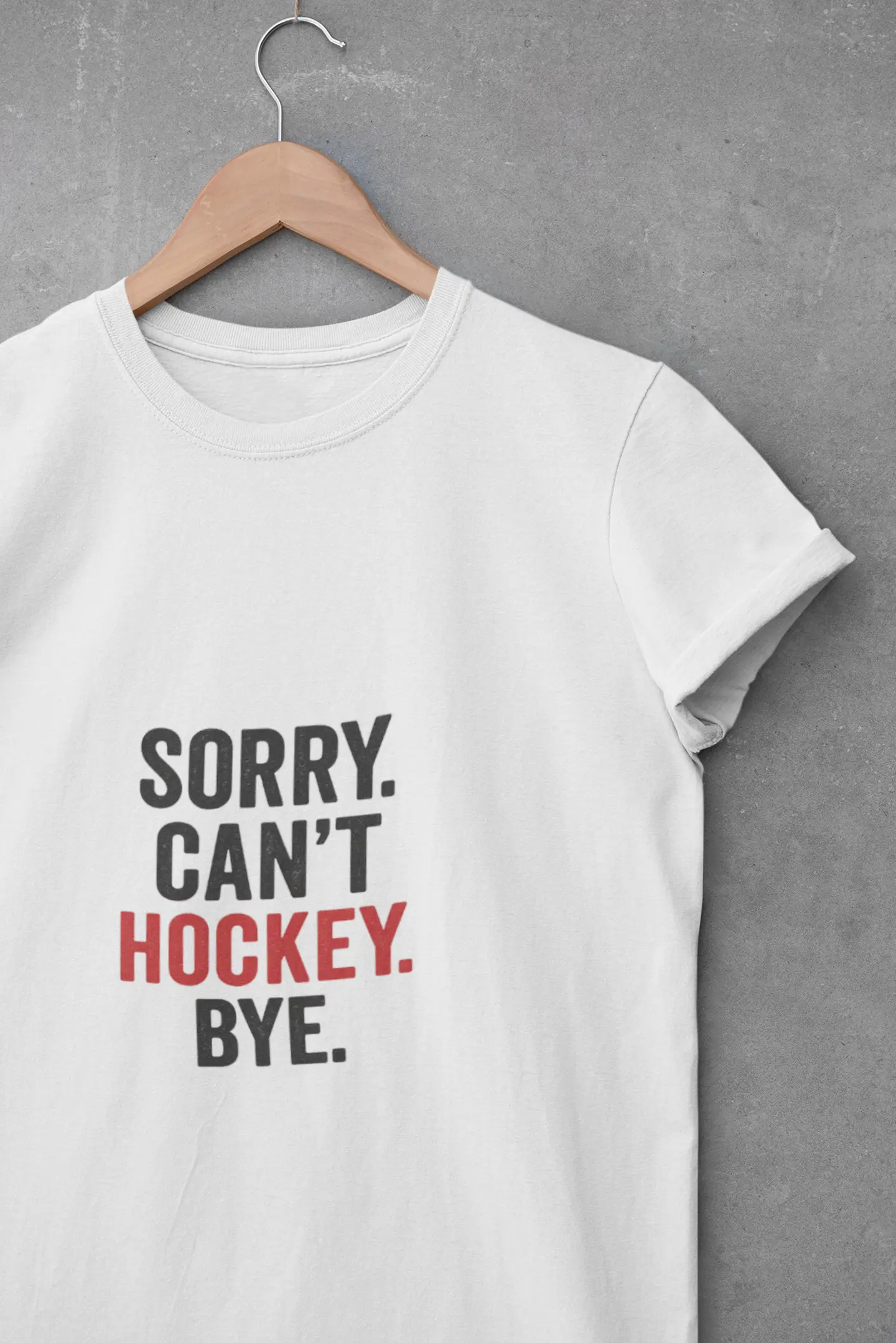 White T-shirt on hanger with 'Sorry. Can't. Hockey. Bye.' black and red text graphic on front against gray background