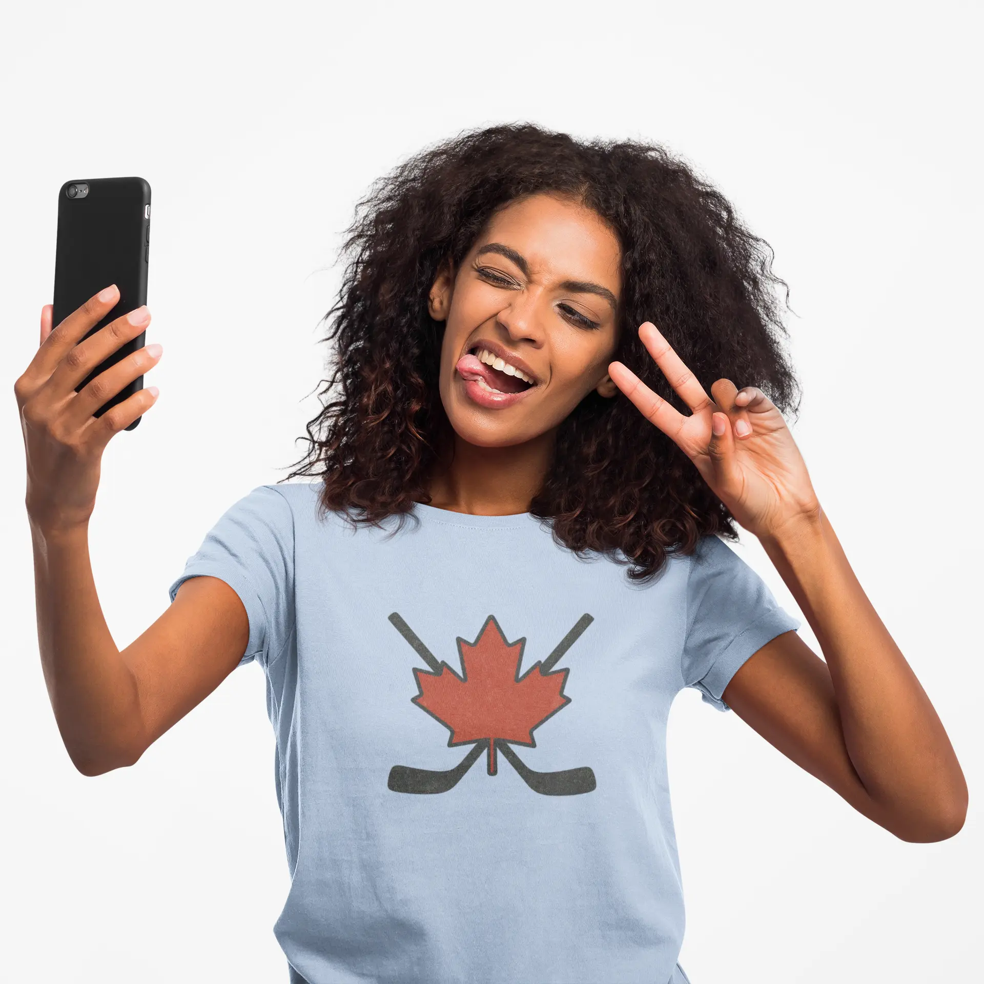 Woman wearing a light blue Maple Leaf Hockey Sticks women’s T-shirt taking a selfie with red maple leaf and crossed hockey sticks graphic