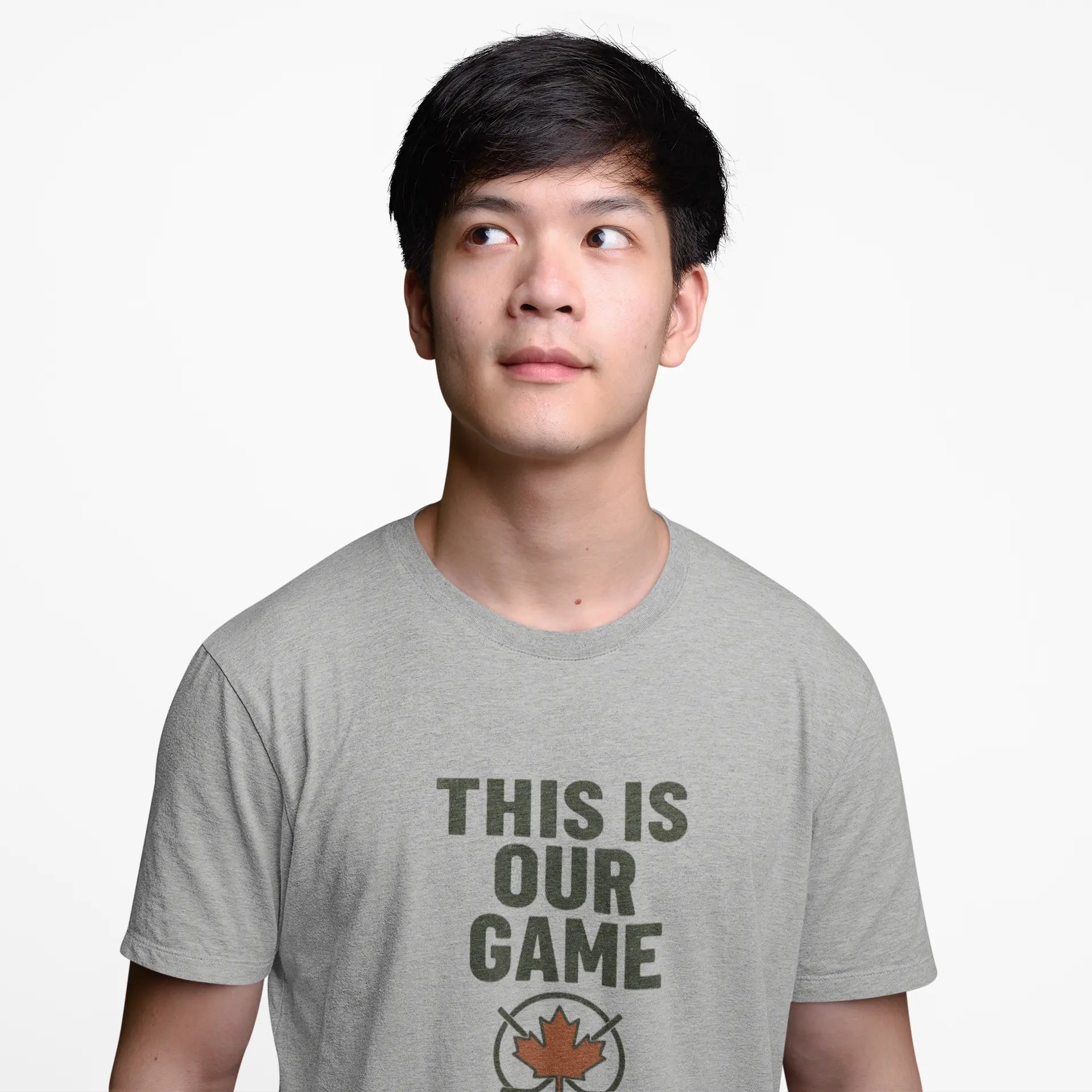 Boy wearing grey 'This Is Our Game' youth T-shirt with maple leaf graphic on a white background – Maple Stick Hockey product.